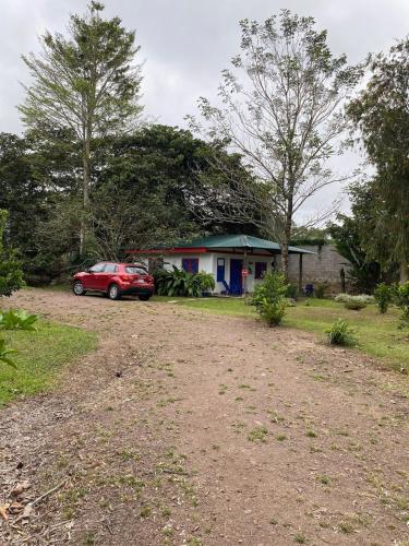 a red car parked in front of a house at Jicote cabañas in Paraíso