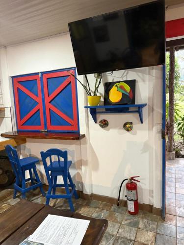 a living room with two blue chairs and a flat screen tv at Jicote cabañas in Paraíso