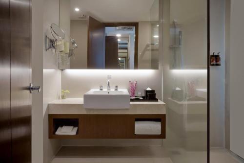 a bathroom with a sink and a mirror and a shower at The Alana Surabaya in Surabaya