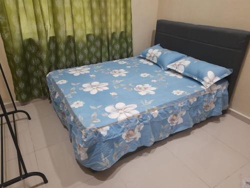 a bed with a blue comforter with flowers on it at Laman Nazira Kia in Kampong Ijok