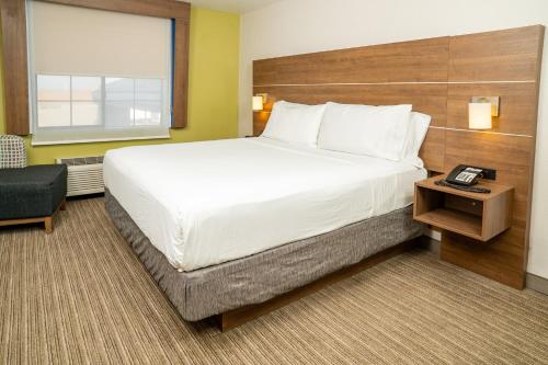a large bed in a hotel room with a telephone at Holiday Inn Express Hotel & Suites Hesperia by IHG in Hesperia