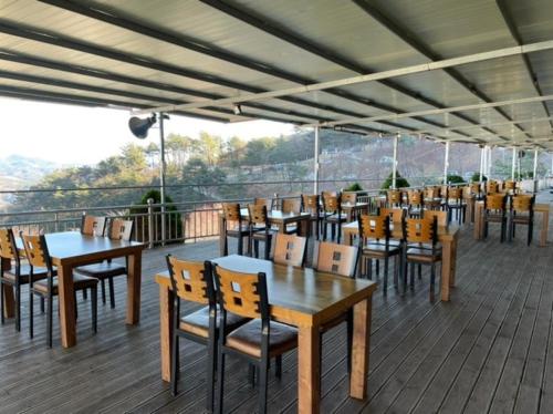a restaurant with tables and chairs on a deck at Venetian Terra KM LAND VTKL 하동 금오산 랜드 숲 캠핑장 