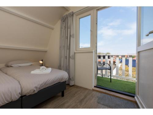 Un dormitorio con una cama y una ventana grande. en Coastal Apartment in Westkapelle, en Westkapelle