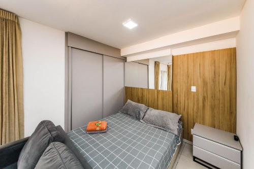 a small bedroom with a bed with an orange bag on it at Stúdio Royal Central piscina/academia/coworking in Juiz de Fora