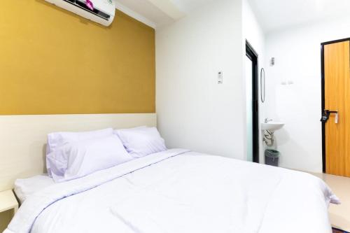 a bedroom with a white bed with a yellow wall at Escotel Journey Hotel Antapani in Bandung