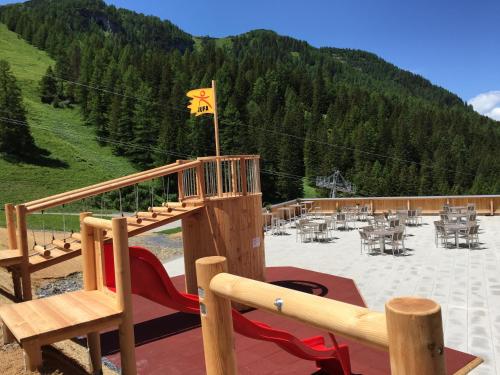 a wooden deck with a playground with tables and a flag at JUFA Hotel Malbun in Malbun