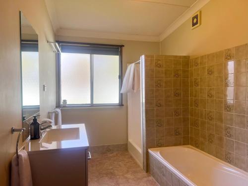 Un baño con bañera, lavabo y ducha. en Rhoda Avenue Residence, en Wagga Wagga