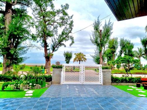a garden with a white gate and trees at Sea la vie - Do Son Beach Homestay in Ðố Sơn