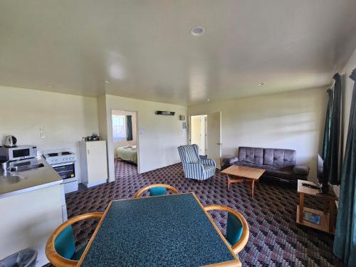 a kitchen and living room with a table and a couch at Karamea Hotel in Karamea