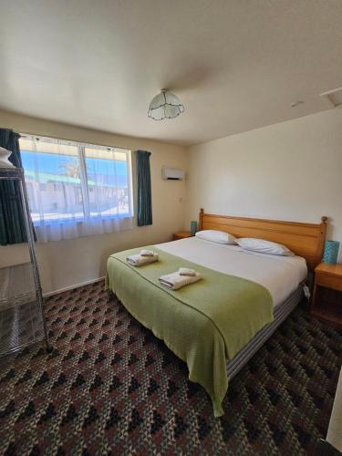a bedroom with a bed and a large window at Karamea Hotel in Karamea