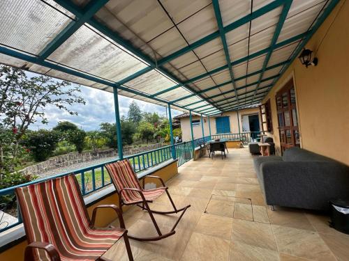 a screened in porch with chairs and a couch at Internacional Hostel Coffee Area in Armenia