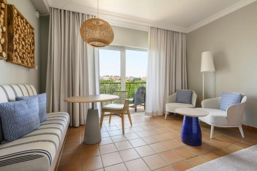 a living room with a couch and a table and chairs at Praia D'El Rey Marriott Golf & Beach Resort in Casal da Lagoa Seca