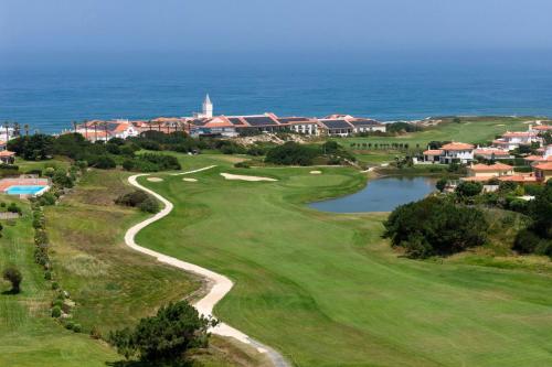 a golf course with the ocean in the background at Praia D'El Rey Marriott Golf & Beach Resort in Casal da Lagoa Seca