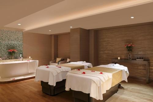 a hotel room with three beds and a bath tub at Novotel New Delhi Aerocity in New Delhi