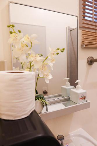 a bathroom with a mirror and white flowers on a sink at AV Suites in Puerto Galera