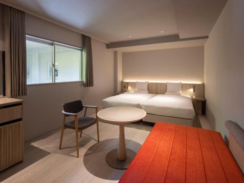 a hotel room with a bed and a table and chair at KAMENOI HOTEL Arima in Kobe