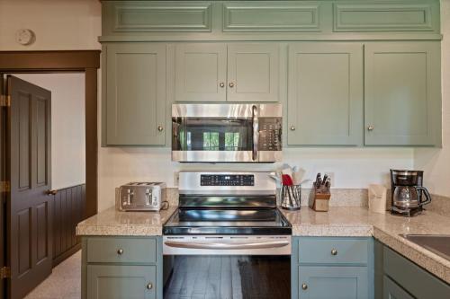 a kitchen with green cabinets and a stove top oven at Metolius Cabin 5 in Camp Sherman