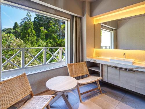 a bathroom with a table and two chairs and a window at KAMENOI HOTEL Arima in Kobe