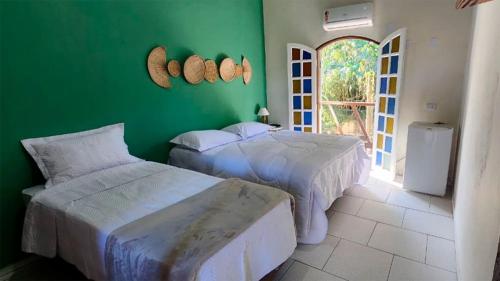 two beds in a room with a green wall at Pousada Numar Maresias in Maresias