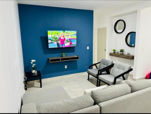 a living room with a couch and a blue wall at Haven de descanso y relajación in Puerto Morelos