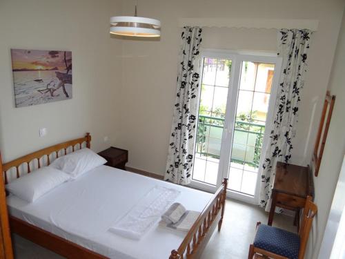 a bedroom with a white bed and a window at Tassos Village House in Moraitika