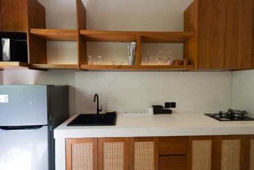 a kitchen with a sink and a refrigerator at Casa Komang, lovely studio in central Bingin in Uluwatu