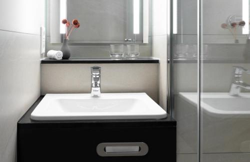 a bathroom with a sink and a glass shower at Leonardo Hotel Nürnberg in Nürnberg