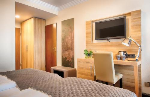 a hotel room with a bed and a flat screen tv at Leonardo Hotel Hamburg Stillhorn in Hamburg