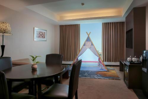 a living room with a table and a large window at The Alana Surabaya in Surabaya