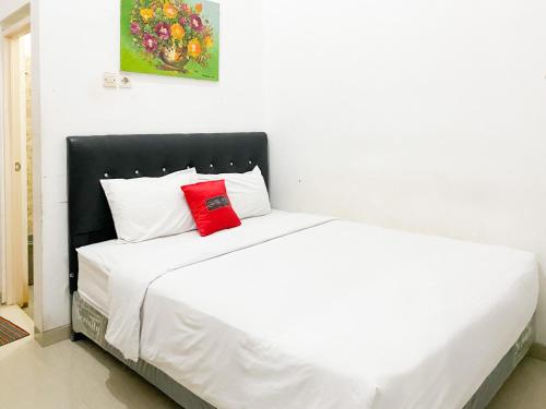 a white bed with a red pillow on it at De Zity Syariah RedPartner Near Alun Alun Jember in Jember