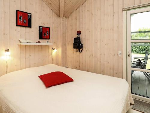 a bedroom with a white bed with a red pillow on it at 8 person holiday home in Fjerritslev in Fjerritslev