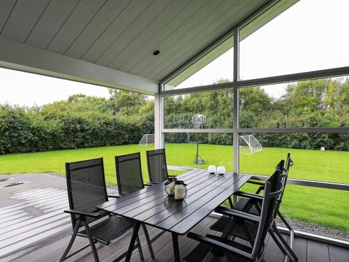 a wooden table and chairs on a screened in porch at 8 person holiday home in Fjerritslev in Fjerritslev