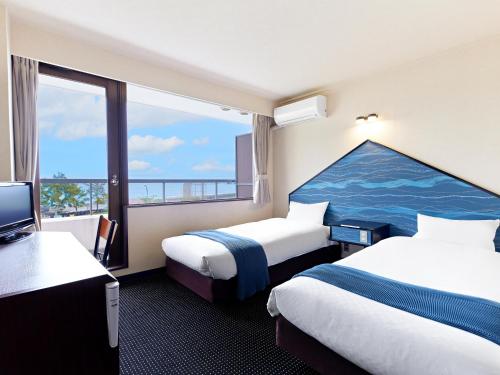 a hotel room with two beds and a large window at Pals Inn Katsuura in Katsuura