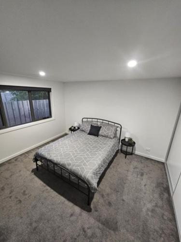 a white bedroom with a bed and two tables at George Town Villa - Outdoor Alfresco - aircon FREE WIFI - Central location near MTB Trails in George Town