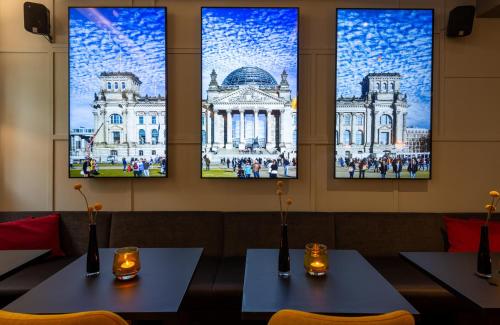 two tables in a restaurant with three windows at Leonardo Royal Hotel Berlin Alexanderplatz in Berlin