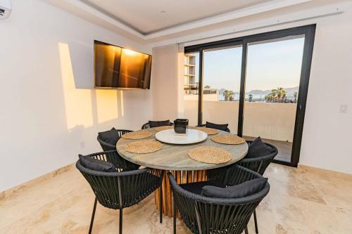 a dining room with a table and chairs and a window at Beautiful apartment with a view of the Arch in Cabo San Lucas