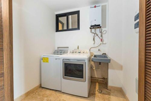 a small kitchen with a washing machine and a sink at Beautiful apartment with a view of the Arch in Cabo San Lucas