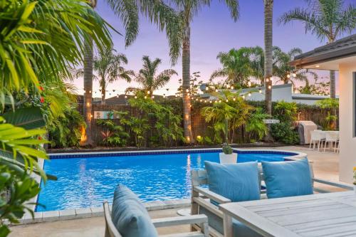 a patio with a table and chairs next to a swimming pool at JB's Sanctuary - Papamoa Holiday Home in Papamoa