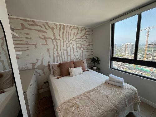 una camera da letto con un letto e una grande finestra di Depto Estudio frente a Mall Plaza Egaña a Santiago