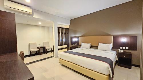 a hotel room with a large bed and a desk at Grage Hotel Malang by TOS in Blimbing
