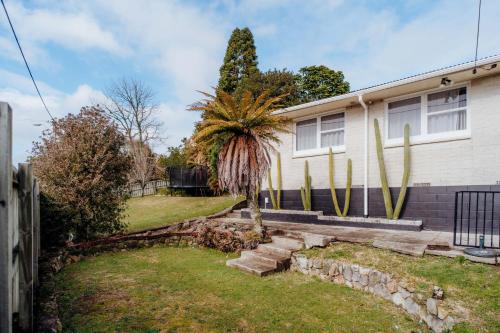 a house with a palm tree in the yard at 3 Bedroom House Rotorua Fully Fenced & Secure in Rotorua
