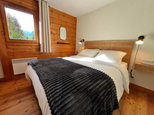 a bedroom with a large bed with a window at Appartement charmant et central à Samoëns, proche commerces et ski-bus - FR-1-624-54 in Samoëns