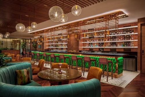 a restaurant with a bar with green chairs and tables at JW Marriott Mumbai Juhu in Mumbai
