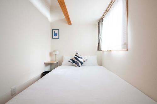 a white bed in a room with a window at KAYA Stay Yokohama in Yokohama