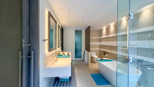 a bathroom with two sinks and a tub and a toilet at Mia Resort Nha Trang in Nha Trang