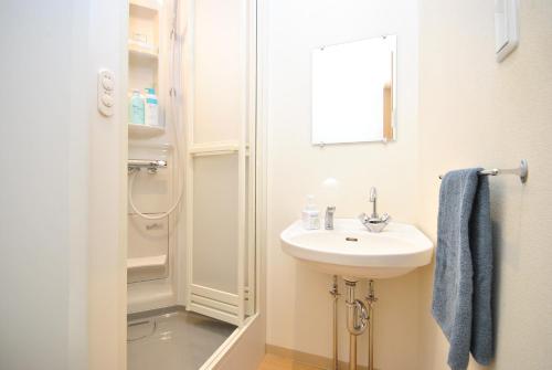 a white bathroom with a sink and a shower at KAYA Stay Yokohama in Yokohama