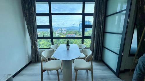 a table and chairs in a room with a large window at JQ1 SEA & POOL or CITY View WIFI I WASHING MACHINE for Some Units I CUCKOO WATER Jesselton Quay by R2 in Kota Kinabalu