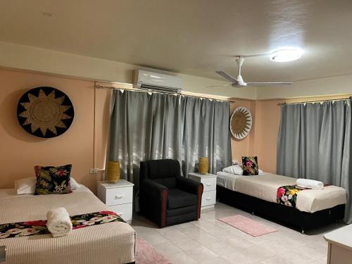 a bedroom with two beds and a chair and a window at Libby's Vacation Rental 2 Bed Home 1-4 Guests in Nadi