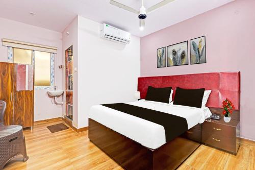 a bedroom with a large bed with a red headboard at Super Hotel O Ramarvapadu Near ESI Hospital in Vijayawada