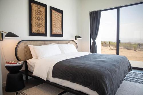 a bedroom with a bed and a large window at White Casita by Fieldtrip - Modern w Pool Spa in Joshua Tree